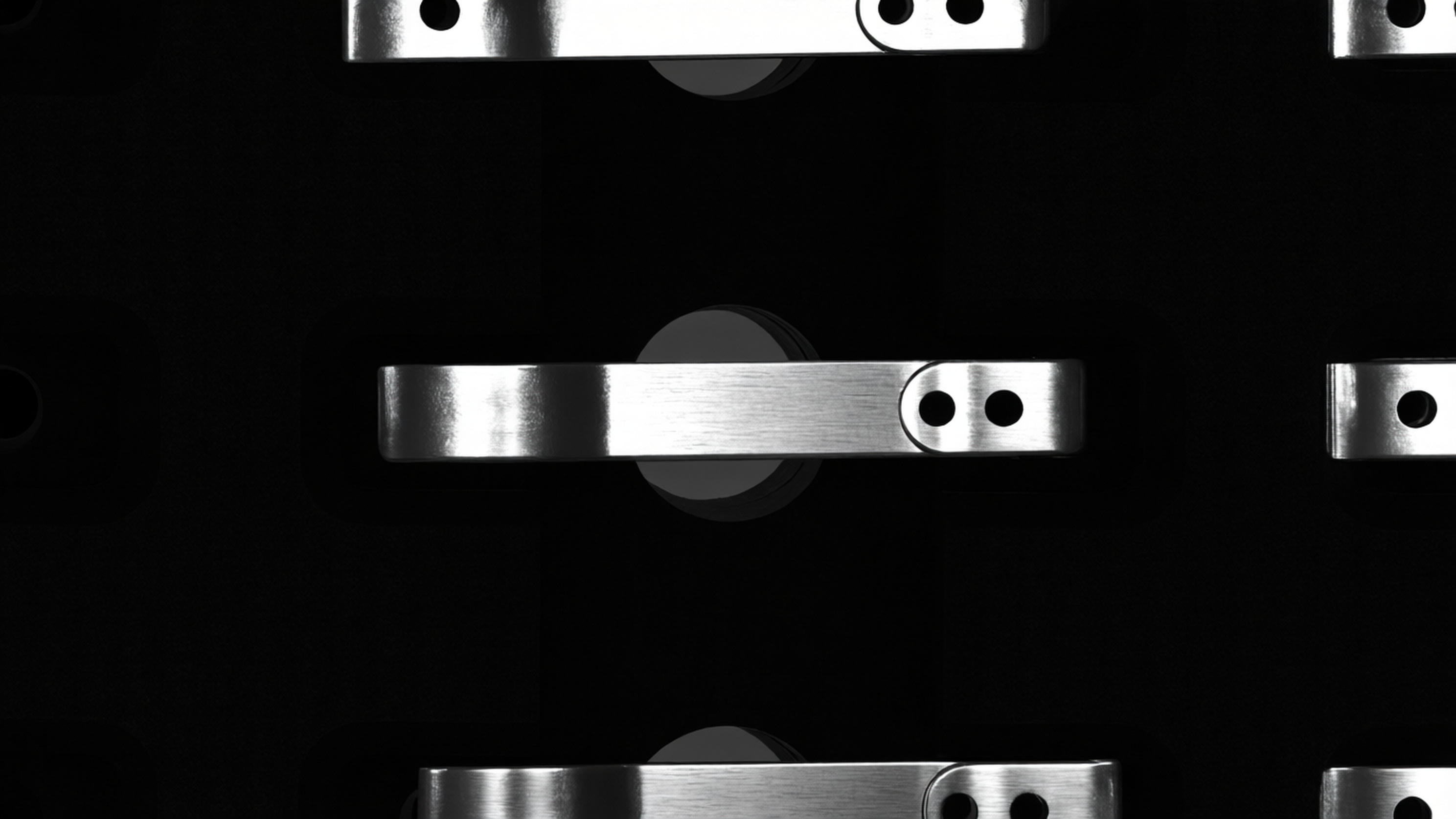 Top-down dark-field view of brushed aluminum lever components with circular mounts and paired holes, arranged in a repeating inspection grid