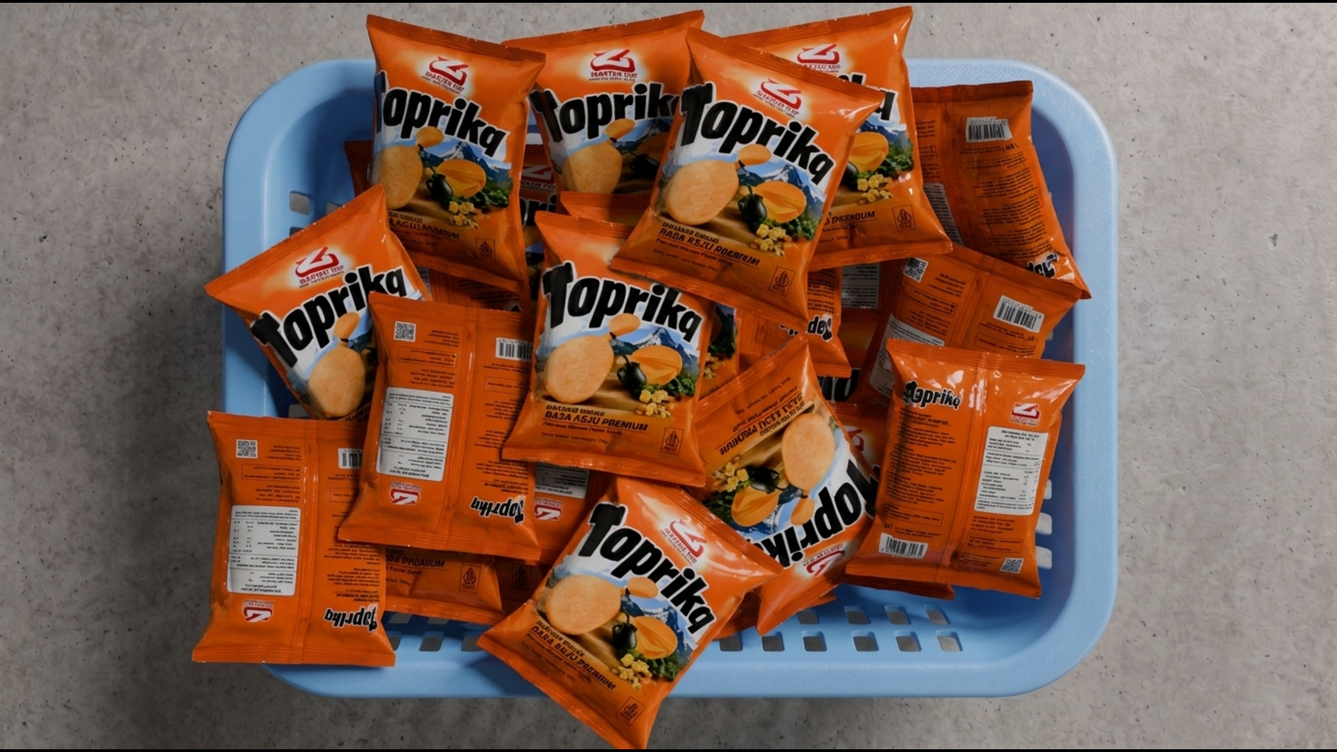 Top-down view of orange Toprika chip bags in a light blue ventilated crate, with Cyrillic branding and a mix of front artwork and white back panels